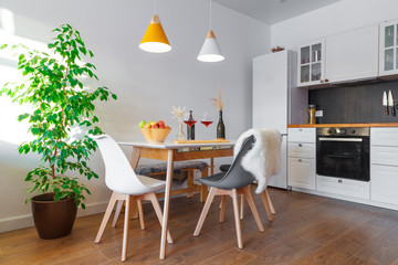 Modern interior cozy kitchen, dining room, white furniture, lamps, wooden table, red wine, glasses....