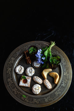 Traditional tea with mint and assorted homedade Arab sweets on dark background. Ramadan. Islamic. Halal