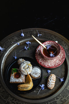Traditional tea with mint and assorted homedade Arab sweets on dark background. Ramadan. Islamic. Halal