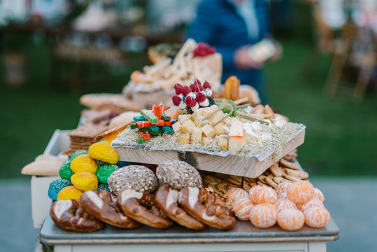 Wooden tray with canapes placed on tray with cookies and fruits in candy bar served during wedding ceremony outdoors