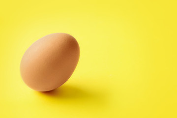 Raw chicken egg on yellow background. Space for text