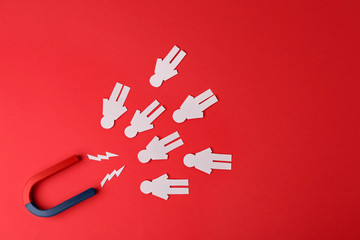 Magnet and paper people on red background, flat lay