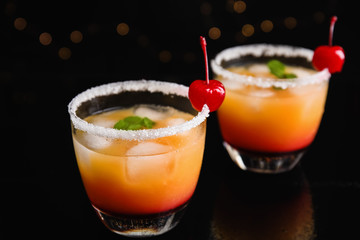 Fresh alcoholic Tequila Sunrise cocktails on black table