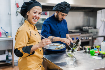 Professional chefs preparing dish in restaurant kitchen