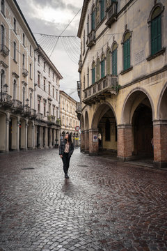 Female traveler in warm clothing walking on block stone road among historical beautiful buildings at Padova at Italy