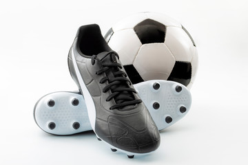Competitive team sports, active life hobbies and athletic gear concept with old-fashioned black leather football cleats or athletics boots with laces and soccer ball isolated on white background - Powered by Adobe