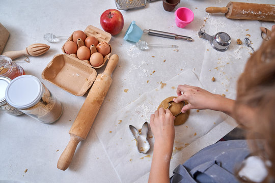 From above unrecognizable cropped hands of child modeling cookies with muffin tin on table at kitchen