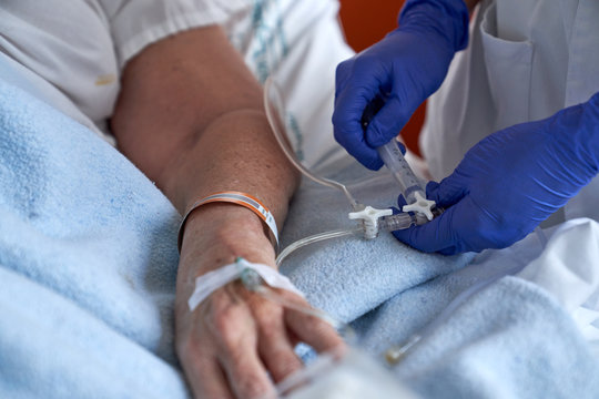 Crop nurse injecting medication into mature patient arm