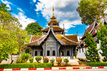 Wooden pagoda temple near Wat Chedi Luang temple in Chiang Mai city, Thailand. Buddhist spiritual place, ancient building. Formal garden before house, summer day. Tourist destination in Asia.
