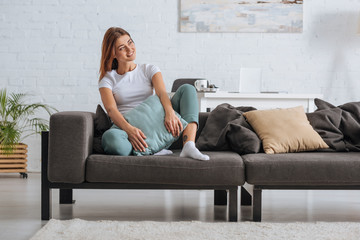 smiling girl looking away while relaxing on sofa with pillow