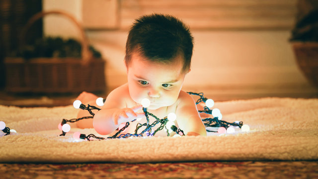Baby playing with light garland on Christmas Day