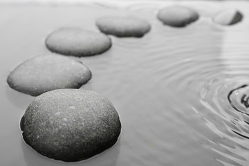 Fototapeta na wymiar Beautiful spa stones in water, space for text. Zen lifestyle