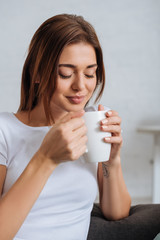young woman with closed eyes holding cup of tea