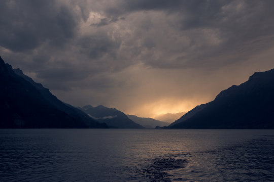 Calm landscape of dark rippled water under gray cloudy sky in mountains in Switzerland