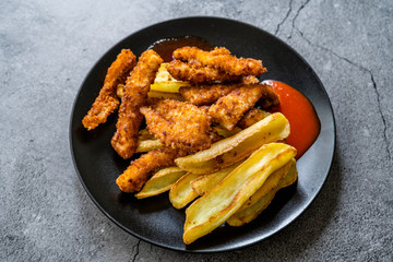 Fish and Chips made with Breaded and Fried Seabass in Black Plate.