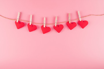 Red heart shape decoration hanging on line with copy space for text on pink background. Love, Wedding, Romantic and Happy Valentine day holiday concept