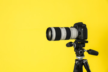Modern professional video camera on yellow background