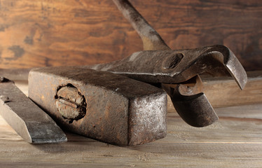 Chisel, hammer and tongs of a blacksmith on a wooden table