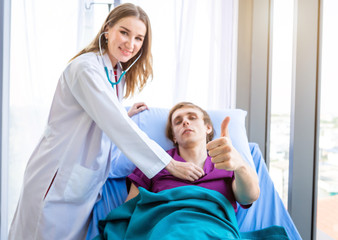Fototapeta premium a man patient on bed Abstract blur with focus show showing thumbs up with smiley face very good symptom to female doctor in hospital background.