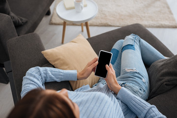 overhead view of woman holding smartphone with blank screen while chilling at home