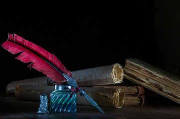 Quill pen and rolled up papyrus sheets with old books