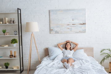 happy woman with tattoo lying while resting in bedroom - obrazy, fototapety, plakaty