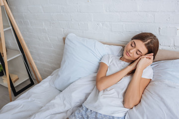 attractive woman dreaming while lying on bed at home