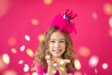 Fototapeta na wymiar Fancy girl blowing confetti against pink bakground