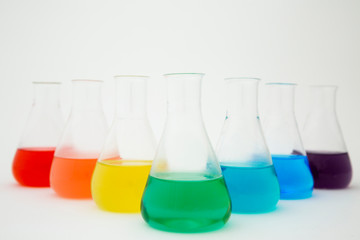 Scientific laboratory glass erlenmeyer flask filled with colorful liquid forming rainbow on white...
