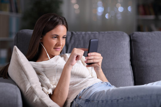 Relaxed girl lying listening to music on mobile phone