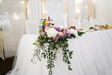 Table set for wedding reception with candles and flower bouquets. Wedding. Banquet. The chairs and round table for guests, served with cutlery, flowers and crockery and covered with a tablecloth.