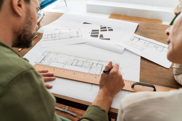 Crop view of two architects working together at desk in office