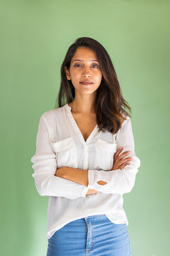 Portrait of young businesswoman standing in front of green wall