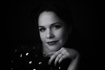 portrait of a woman on a blurred black background. black and white image. film grain.
