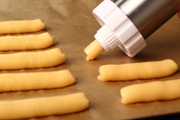 Pipe choux pastry onto baking tray. Making Eclair.