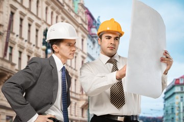 Two engineers men at construction site watching blueprint