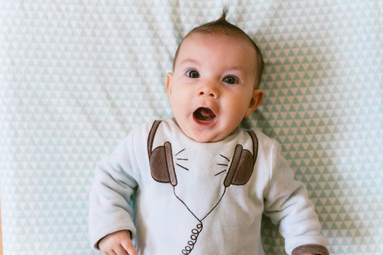 Portrait of surprised baby girl with appliqued headphones on pajamas
