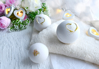 Romantic spa cosmetic composition. Close up bath bombs, roses, hearts, towel on white background. Love or health lifestyle concept