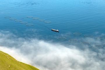 Fototapeta premium Fish farm with ship on foggy fjords of Funningur, Eysturoy island, Faroe Islands. Landscape photography