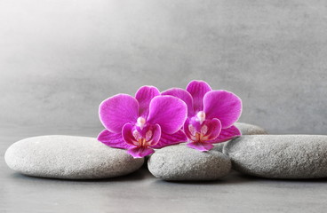 Spa stones and orchid flower on the grey background