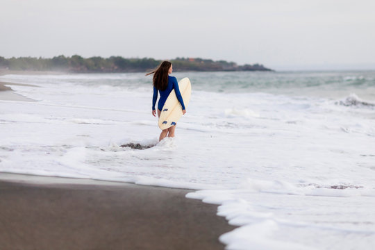 Young woman with surfboard at the beach, Kedungu beach, Bali, Indonesia