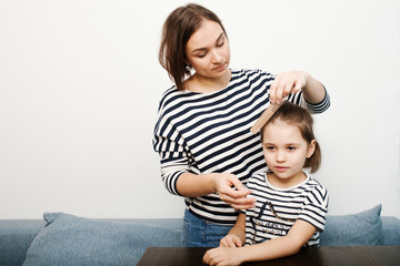 Young mother combs daugther hair at home