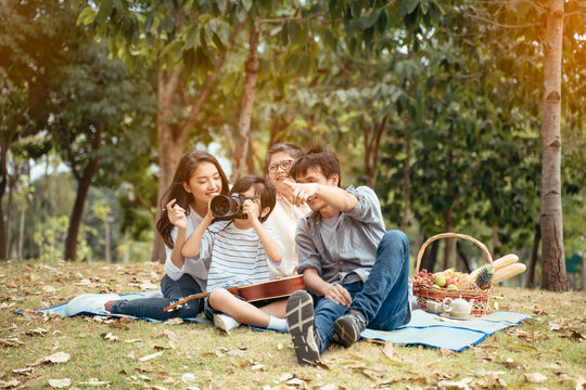 Dad is teaching son taking a photo at the park.Happy Asian family father,mother,son and grandmother enjoy picnic time at the park.The concept of family relaxed activity in holiday.