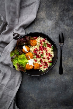 Bowl of?falafel?with lettuce, yogurt, pomegranate seeds, parsley, mint and Tabbouleh salad