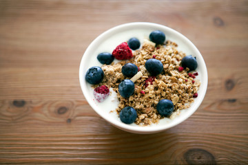 Delicious yogurt breakfast bowl with muesli and fresh blackberries on a wooden table and linen kitchen-towel. Healthy and organic nutrition concept. Blackberry and raspberry muesli. Yogurt in a bowl