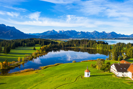 Germany, Bavaria, Halblech, Aerial view of small chapel, farmhouse and Hegratsrieder See lake in Tannheim Mountains