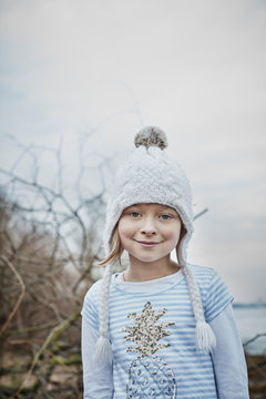 Portrait Of Smiling Little Girl Wearing Bobble Hat In Nature