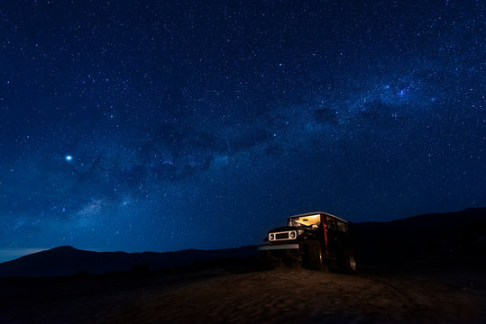 Indonesia, East Java, Milky Way galaxy on blue starry night sky over car parked in Bromo Tengger Semeru National Park