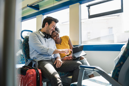 Happy young couple using tablet in a train