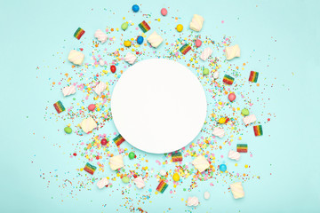 Colorful flat lay composition with various party items and candies on blue background